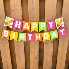 a happy birthday banner hanging from a wooden fence with pineapples and cherries on it