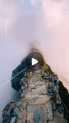 an aerial view of the top of a mountain with fog coming from it and a video player standing at the bottom