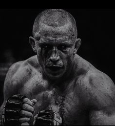 a black and white photo of a man with mud on his face holding a boxing glove