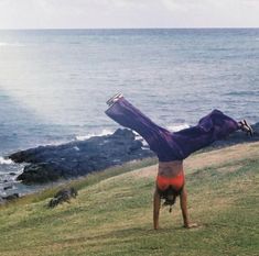 a person doing a handstand in front of the ocean