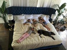 four people and a dog laying on a bed