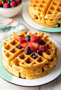 two plates with waffles and berries on them