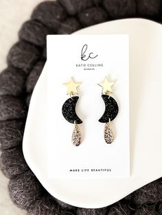 Welcome to Katie Collins Design Co. How cute are these celestial inspired gold star and crescent moon dangle earrings! Handmade from polymer clay, the moon features black clay with gold glitter to give it that extra celestial feel with a delicate teardrop covered in textured gold foil. Attached to beautiful gold brass star earring posts, these dangles are absolutely perfect to wear for this years much anticipated solar eclipse. Not to mention they would be the perfect gift for any astrology lover, science teacher or star gazing friend in your life! Truly one-of-a-kind, all of my earrings are lovingly handmade by me with extremely lightweight polymer clay and come on pretty jewelry cards making them perfect to gift. I also offer FREE shipping on all orders over $35 as well as a FREE gift wi Crescent Moon Clay Earrings, Moon Earrings Clay, Polymer Clay Moon, Holiday Jewelry Ideas, Collins Design, Clay Moon, New Eve, Earring Inspo, Star Earring