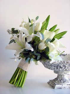 a bouquet of white flowers sitting on top of a table next to an urn