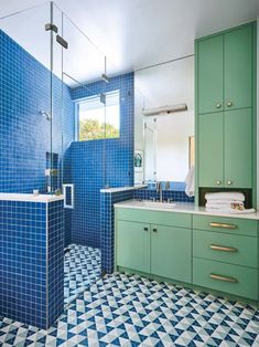 a bathroom with blue and green tiles on the floor, shower stall, sink and bathtub