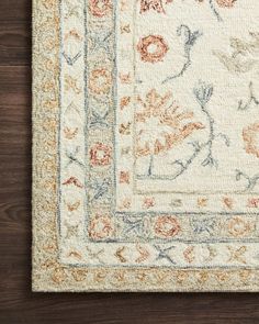 an area rug with flowers and leaves on the bottom is shown in white, orange and blue