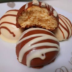 three chocolate covered desserts sitting on top of a white plate