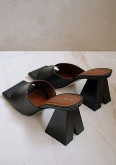 A bold statement heel adds interest to this classic black leather slip-on mule sandal. Featuring a trendy square toe and a pyramid-shaped block heel with a notched cutout detail. We love to style it with jeans or a simple mid-length dress. Leather Open toed Square sole Slip on Pyramid block heel with notched cutout Fits true to size. If you are in-between sizes, we recommend sizing up. Heel Height: 3"Made in Spain Inspired by endless summer, Alohas are designed in Barcelona and handcrafted in Sp Black Block Heel Sandals, Sustainable Leather, Vegan Boots, Black Block Heels, Block Heel Sandals, Black Leather Sandals, Mule Sandals, Designer Heels, Block Heels Sandal