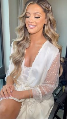 a woman with long hair sitting in a chair wearing a white dress and pearls on her head