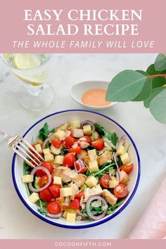 a salad in a blue and white bowl on a marble table next to a glass of water