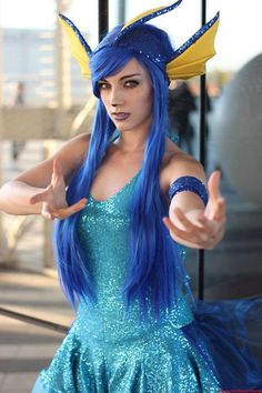 a woman with blue hair wearing a costume and pointing her finger at something in the air