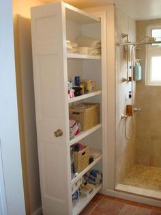 a walk in shower sitting next to a white cabinet filled with bottles and soaps