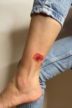 a small red flower tattoo on the ankle