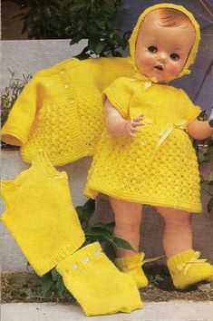 a baby doll is wearing a yellow knitted outfit and booties