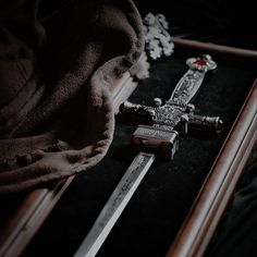 two swords are laying on the ground next to some other items that have been placed in a shadow box