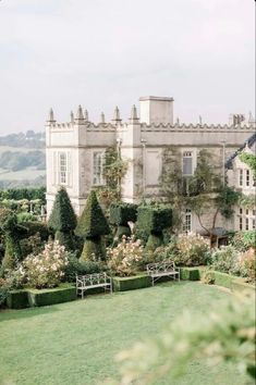 a large building with lots of trees and bushes around it in front of the grass