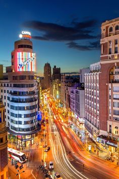 an aerial view of a city street at night with traffic and tall buildings in the background