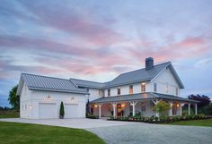 a large white house sitting on top of a lush green field under a cloudy sky