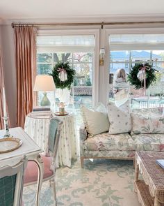 a living room filled with lots of furniture next to a window covered in pink curtains