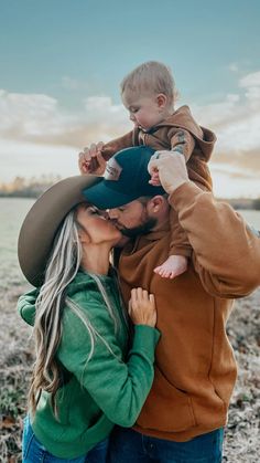 a man and woman are holding a baby in their arms while standing on the beach