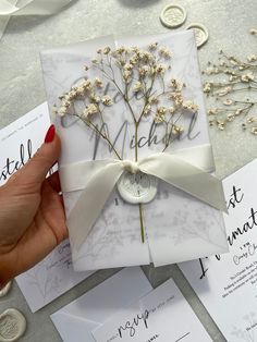 a person holding a wedding card with flowers on it