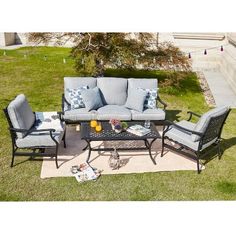 an outdoor patio furniture set with blue cushions and pillows on the grass in front of a house