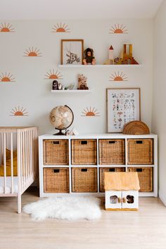 a baby's room with white walls and wooden drawers