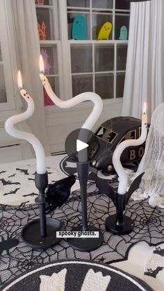 two white candles are on top of a black and white table cloth with an intricate design