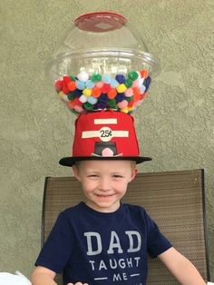 a young boy wearing a hat made to look like a gummy machine with balls on top