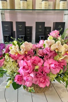 a basket filled with lots of pink and white flowers on top of a wooden table