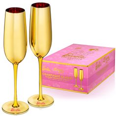 two champagne flutes in front of a pink box with gold lettering on the bottom and sides