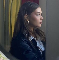 a woman looking out the window while wearing earring's in front of her