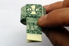 a hand holding a one dollar bill origami