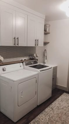 a white washer and dryer in a small room with cabinets on the wall