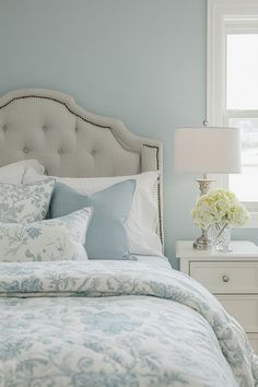 a bedroom with blue walls and white bedding has a floral print comforter on it