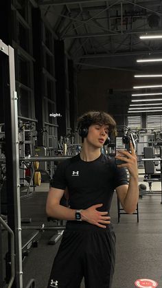 a young man is taking a selfie in the gym with headphones on his ears