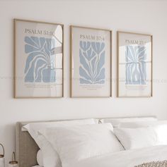 two framed posters above a bed in a room with white linens and neutral colors