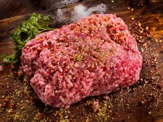 raw ground beef on a cutting board with parsley and seasoning next to it