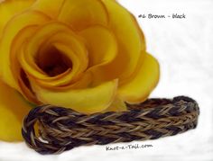 a yellow rose sitting on top of a woven piece of cloth next to a rope