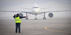 a man in yellow vest standing next to an airplane