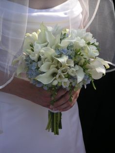 a bride holding a bouquet of white and blue flowers