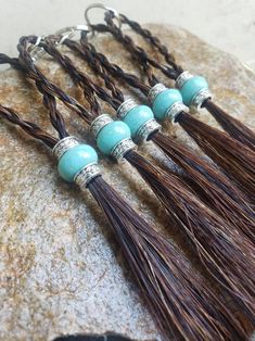 four tassels with turquoise beads and brown leather cord on top of a rock