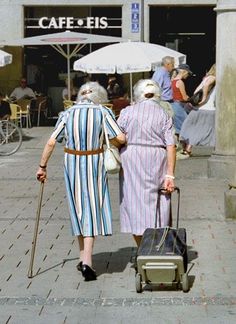 an older couple walking down the street with luggage