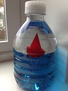 a water bottle with a red paper boat in it