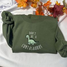 Ready to show everyone your fun side? With this Funny Don't be a cuntasaurus embroidered sweatshirt, you can do just that! It features an embroidered phrase, making it the perfect way to make a statement while still looking stylish. This sweatshirt is comfortable and made of ultra-soft fabric, so you can wear it for any occasion. Whether you're headed out for a night on the town, or just staying in and relaxing, this sweatshirt will keep you stylish and comfortable. With its unique design, this Novelty Cotton Crew Neck Sweatshirt, Casual Dinosaur Print Crew Neck Sweatshirt, Casual Cotton Sweatshirt With Dinosaur Print, Funny Dinosaur, Funny Gifts For Her, Dinosaur Funny, Embroidery Gifts, Funny Christmas Gifts, Embroidered Crewneck