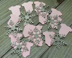 several snowflakes are arranged on a wooden table with pink and silver glitters