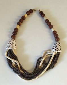 "This necklace has a beautiful carefree beach vibe! Pook a shell and wooden beads with two larger seashell beads on either side. What a great 1980's vintage summer staple.  This is a vintage used item and is in great vintage used condition with little to no wear, there are no missing or broken beads,  It is approximately 22\" in length." Beach Necklace With Brown Round Beads, Vintage Brown Necklaces For The Beach, Adjustable Multi-strand Shell Necklace For Beach, Vintage Brown Jewelry For The Beach, Vintage Brown Beaded Necklaces For Beach, Handmade Multi-strand Shell Necklace For Beach, Beach Necklaces With Colorful Beads In Brown, Bohemian Multi-strand Shell Necklace For Beach, Beaded Brown Necklace For Vacation