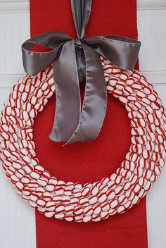 a red and white wreath on top of a red cloth with a gray ribbon tied around it