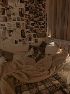 an unmade bed with lots of pictures on the wall and lights in the corner