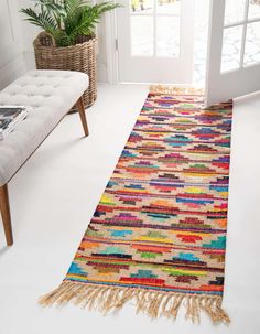 a multicolored runner rug with fringes on the floor in front of a white door